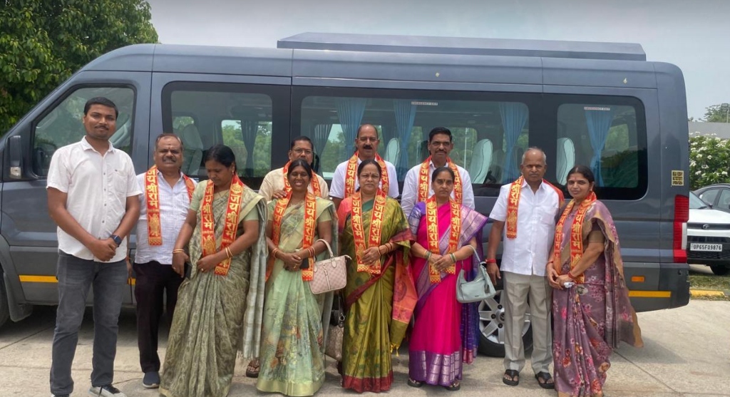 Pilgrims wearing saffron stoles posing with the luxury tour coach.